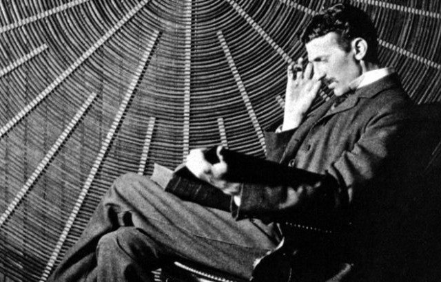 Tesla yüksek gerilim trafosunun sarmal bobininin önünde oturup kitap okurken.